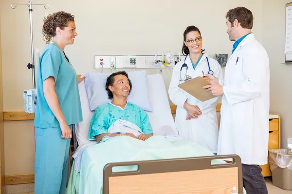 Médicos discutiendo informe mientras enfermera y paciente mirando el —  Fotos de Stock