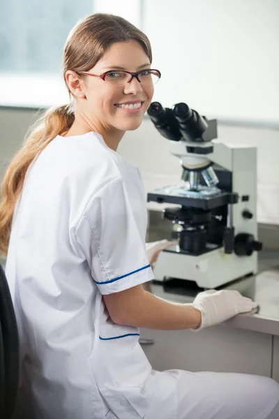 Cientista feminina confiante usando microscópio no laboratório — Fotografia de Stock