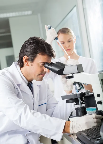 Científico masculino usando microscopio en laboratorio — Foto de Stock