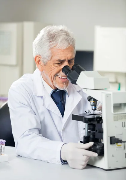 Científico sonriente usando microscopio en laboratorio —  Fotos de Stock