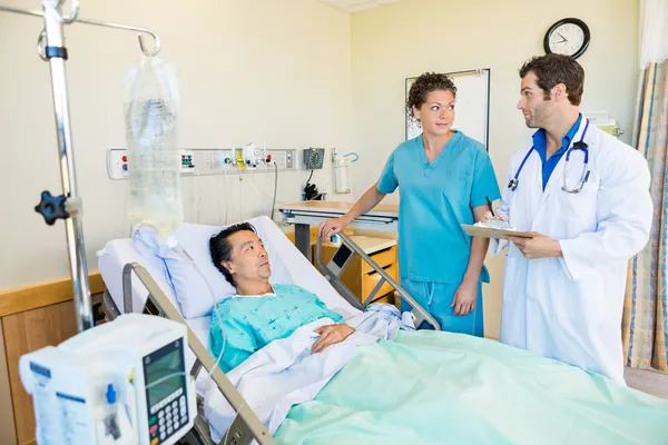 Ärzteteam schaut sich gegenseitig an, während Patient im Bett liegt — Stockfoto