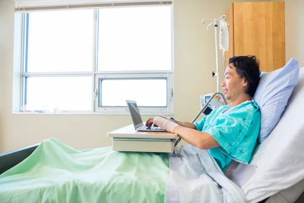 Patienten använder laptop på sjukhussäng — Stockfoto