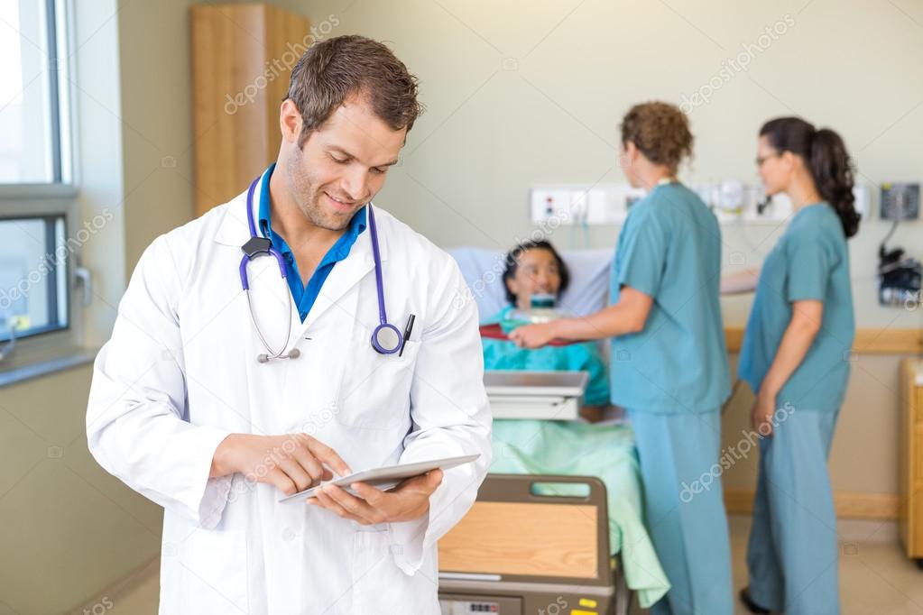 Doctor Using Digital Tablet While Nurses Serving Breakfast To Pa