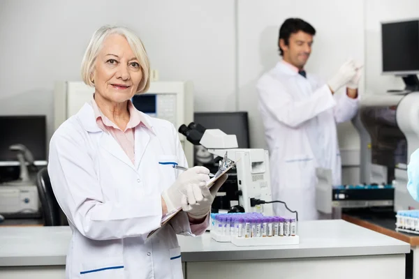 Cientista feminina escrevendo na área de transferência em laboratório — Fotografia de Stock