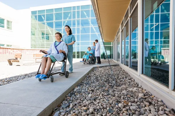 Medisch team met patiënten op rolstoelen in het ziekenhuis courtyard — Stockfoto