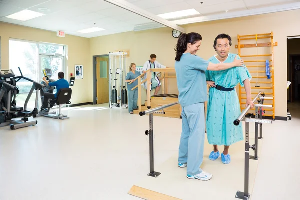 Терапевты, помогающие пациентам в больничном спортзале — стоковое фото