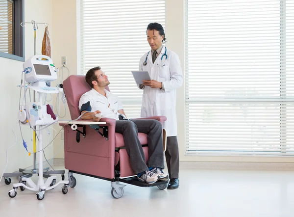 Пацієнт дивиться на лікаря за допомогою цифрового планшета в Chemo Room — стокове фото