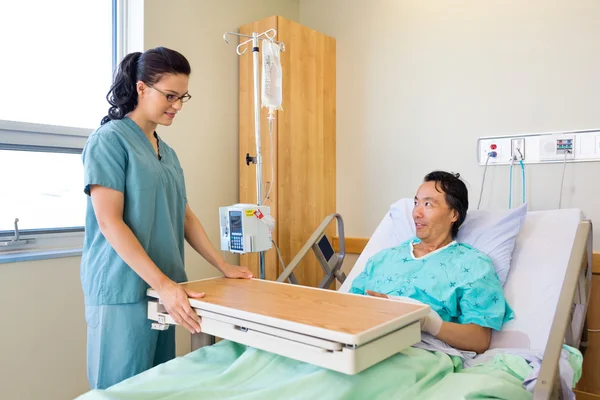 Enfermera colocando mesa sobrecargada para paciente masculino — Foto de Stock