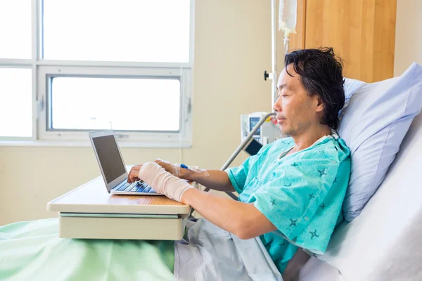 Пациент с помощью ноутбука на кровати в больнице — стоковое фото