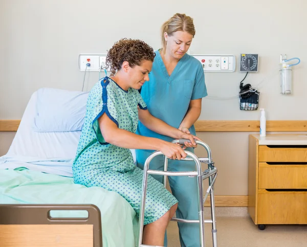 Patiënt met walker terwijl verpleegster haar bijstaan in het ziekenhuis — Stockfoto