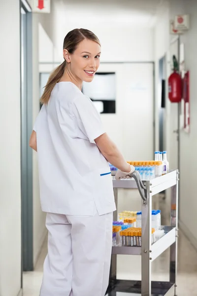 Técnico de laboratorio empujando carro médico en corredor —  Fotos de Stock