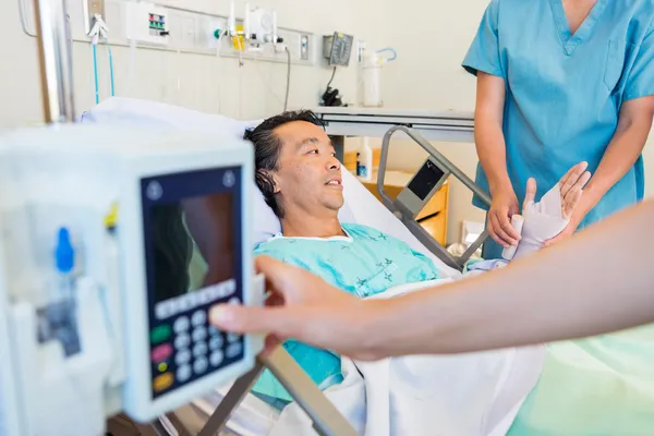 Verpleegkundige zetten pleister op patiënt hand terwijl collega operationele — Stockfoto