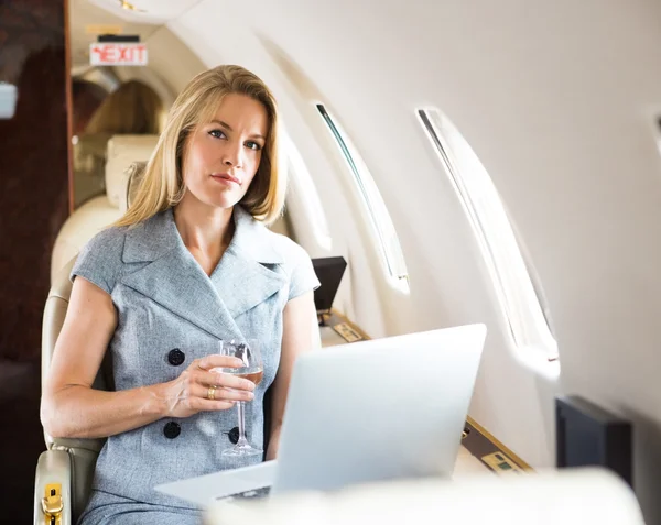 Selbstbewusste Geschäftsfrau mit Weinglas im Privatjet — Stockfoto