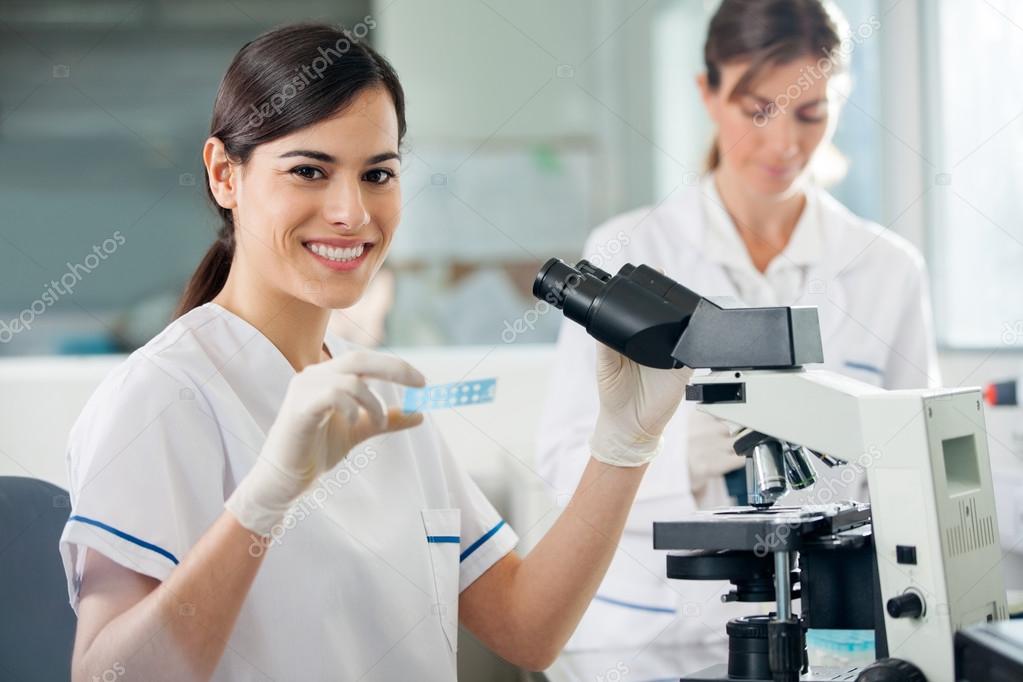 Female Researcher Using Microscope In Lab