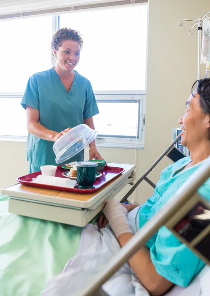 Krankenschwester hebt Deckel von Essteller für Patientin im Krankenhaus — Stockfoto