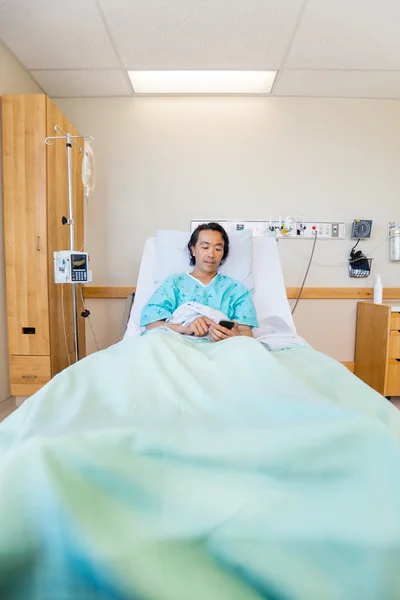 Mensagens do paciente através do telefone móvel na cama do hospital — Fotografia de Stock