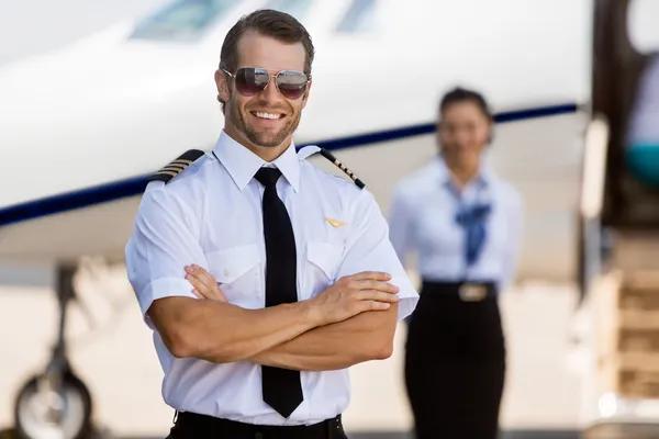 Piloto confiante contra aeromoça e jato privado — Fotografia de Stock