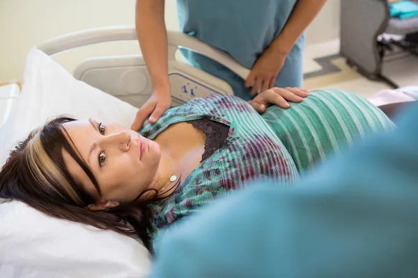 Kobieta w ciąży patrząc pielęgniarka a kolega jej pocieszające — Zdjęcie stockowe