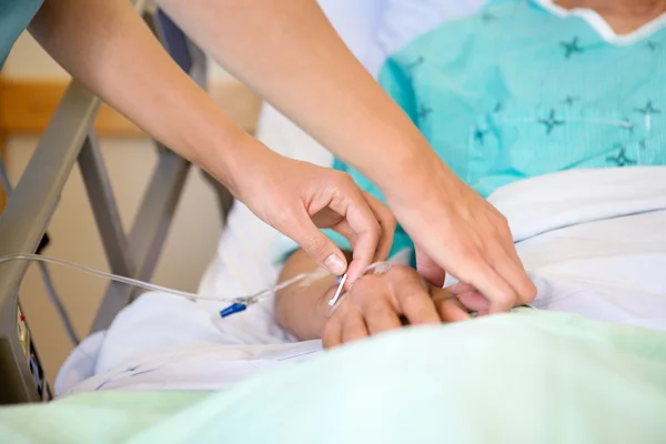 Медсестра прикрепляет капельницу на руку пациента Стоковое Фото