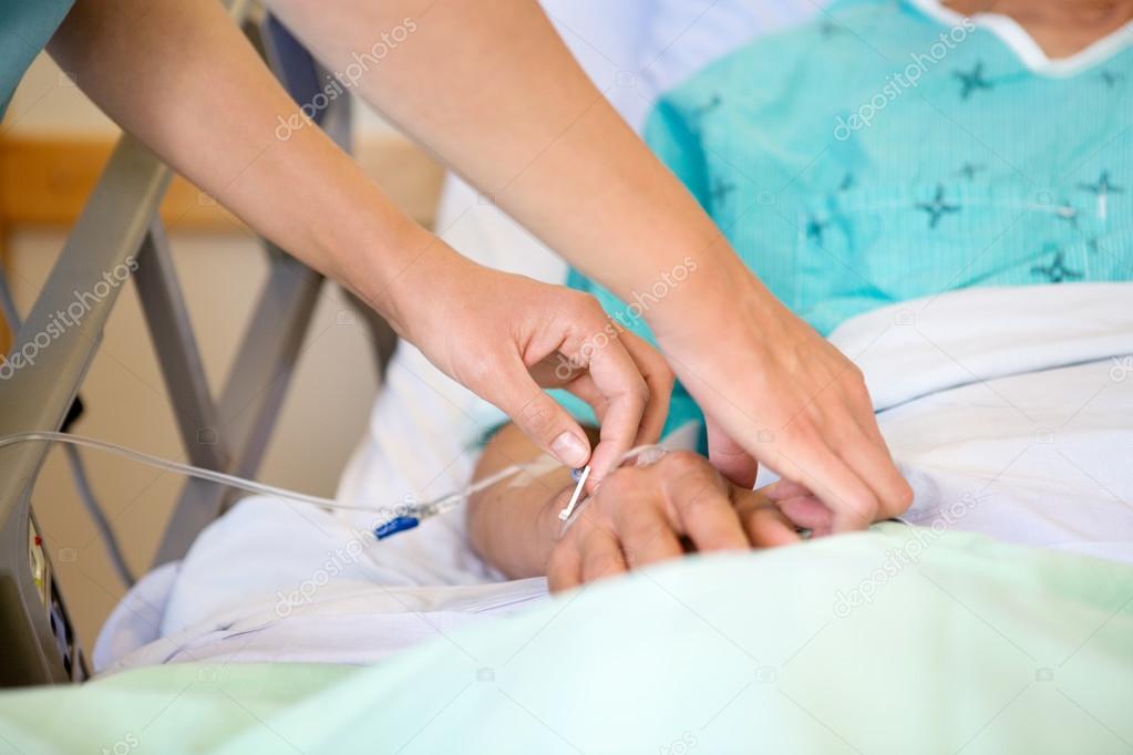 Nurse Attaching IV Drip On Male Patient's Hand