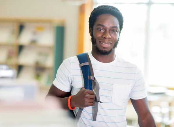 Student står vid bokhyllan i biblioteket — Stockfoto