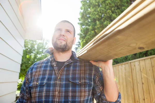 Carpenter Carrying Planks While Looking Away At Site — Stock Photo, Image