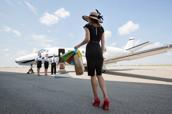 Woman Carrying Shopping Bags While Walking Towards Private Jet