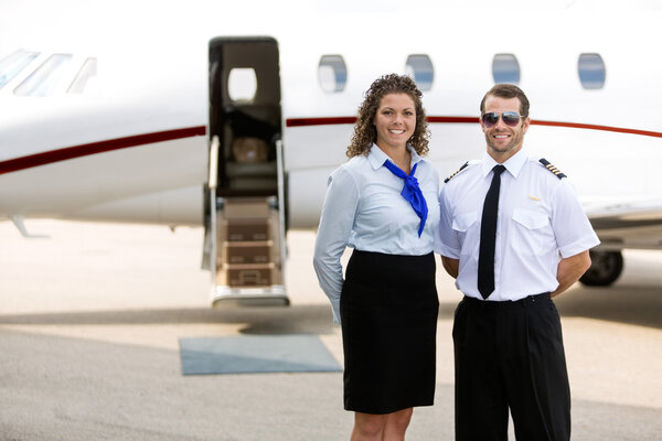 Airhostess And Pilot Standing Against Private Jet