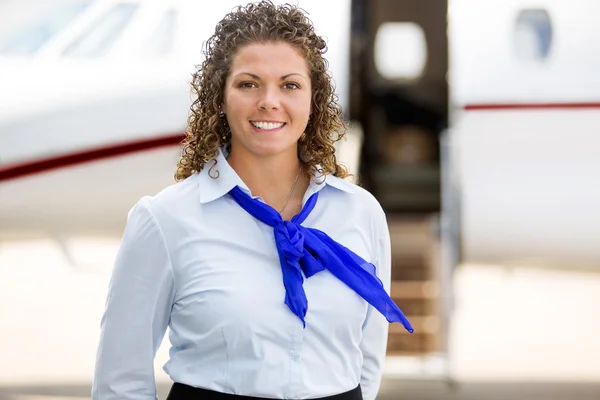 Mooie stewardess met prive-jet op achtergrond — Stockfoto