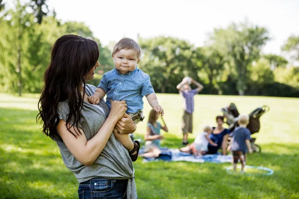 Mãe feliz carregando filho no parque — Fotografia de Stock