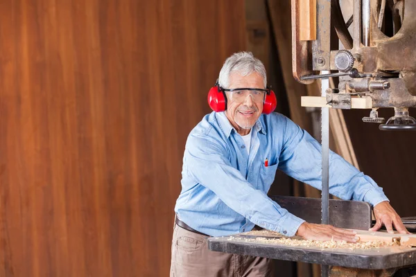 Senior-Schreiner schneidet Holz mit Bandsäge — Stockfoto