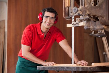 Kendine güvenen marangoz odun kesmek için testere kullanarak