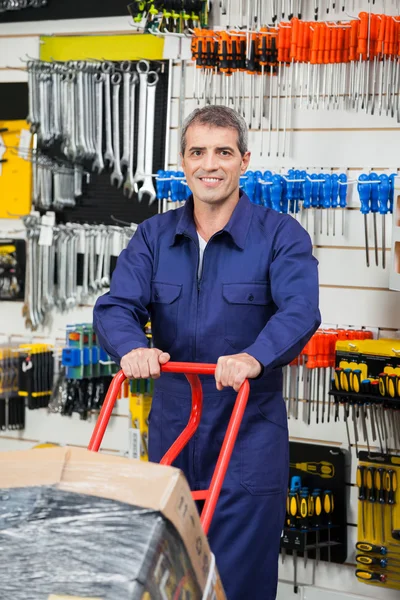 Volwassen werknemer duwen trolley koffer in hardware winkel — Stockfoto