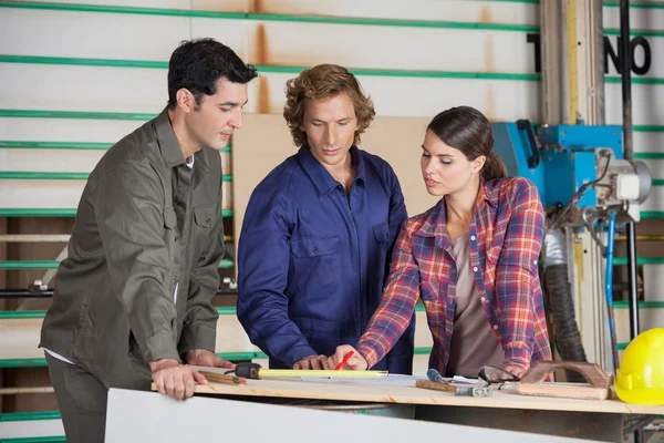 Плотники обсуждают за столом в мастерской — стоковое фото