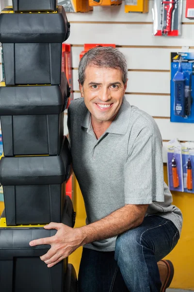 Muž zvedání stohu toolboxy v hardwaru obchodě — Stock fotografie