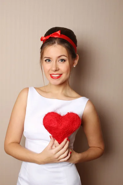 Beautiful young woman holding a red heart — Stock Photo, Image