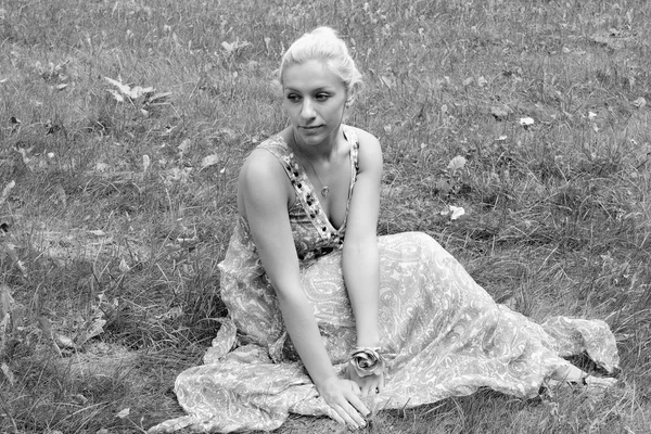Parkta çim üzerinde oturan genç kadın — Stok fotoğraf