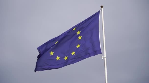 Europeiska unionens flagga viftar i vinden på flaggstången i slow motion på molnig himmel bakgrund — Stockvideo