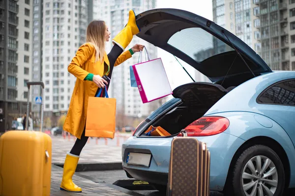Mujer flexible saca el equipaje del coche. Tiempo para viajar y concepto de vacaciones — Foto de Stock