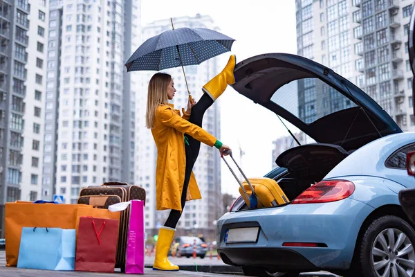 Mujer flexible sosteniendo split y sacando bolsas del coche. Flexibilidad, yoga, estiramiento y concepto de salud — Foto de Stock