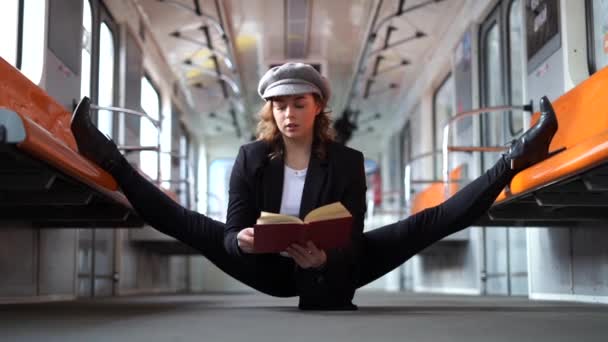 Rugalmas nő ül a hasadékon a metróban, és lassított felvételen könyvet olvas. Az oktatás és az önfejlesztés fogalma — Stock videók
