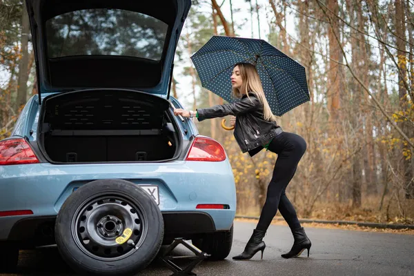 Sexy woman on the heels with broken car on the empty road waits for help. Concept of seduction, erotic and sex — Stock Photo, Image