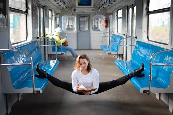 在地下车厢里，柔韧的女瑜伽手坐在体操车厢里看书。灵感、和谐与健康的概念. — 图库照片