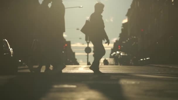 Sylwetka osób przechodzących przez ulicę w zwolnionym tempie podczas zachodu słońca. Koncepcja życia miejskiego i miejskiego — Wideo stockowe