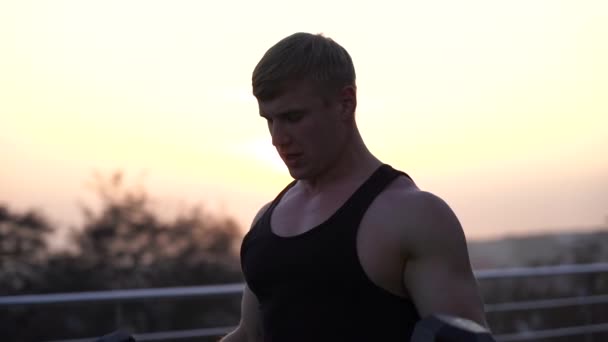 Hombre blanco musculoso caucásico levantando pesas contra el fondo del cielo al atardecer. Concepto de fuerza de voluntad, motivación y pasión — Vídeos de Stock