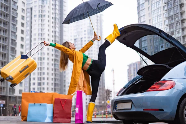Mujer flexible sosteniendo split y sacando bolsas del coche. Concepto de individualidad, creatividad y sobresaliente — Foto de Stock