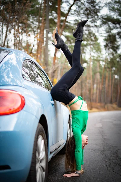Mujer sexy y flexible en los talones con coche en la carretera. Concepto de sexualidad y seducción — Foto de Stock