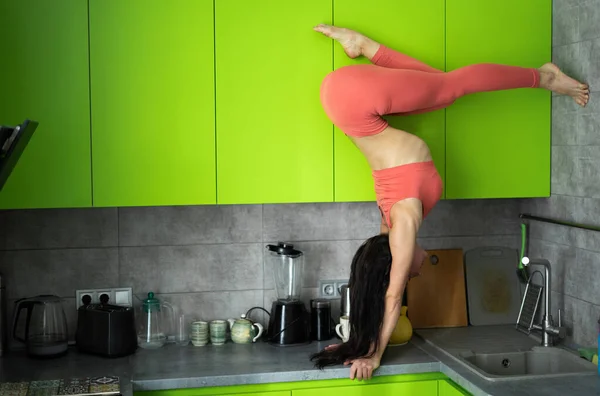 Mulher na cozinha fazendo exercício e suporte de mão. Conceito de individualidade, criatividade e autoconfiança — Fotografia de Stock