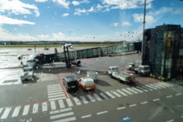 Vliegtuig wachtend op vertrek in luchthaventerminal, wazig horizontale achtergrond met regendruppels. Vervoers- en logistiek concept — Stockfoto