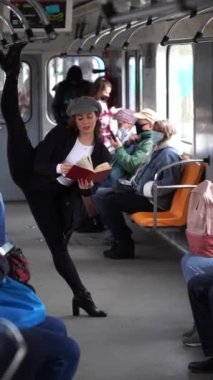 Çok esnek bir kadın metro vagonunda kitap okuyor jimnastik bölümünde duruyor. Sağlıklı yaşam tarzı, esneklik ve yoga kavramı